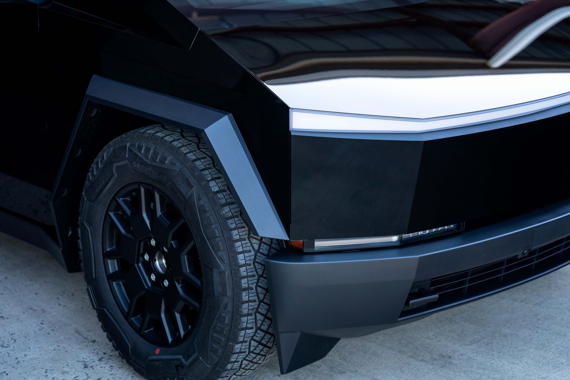 Black Tesla Cybertruck's front quarter panel with a black wheel.