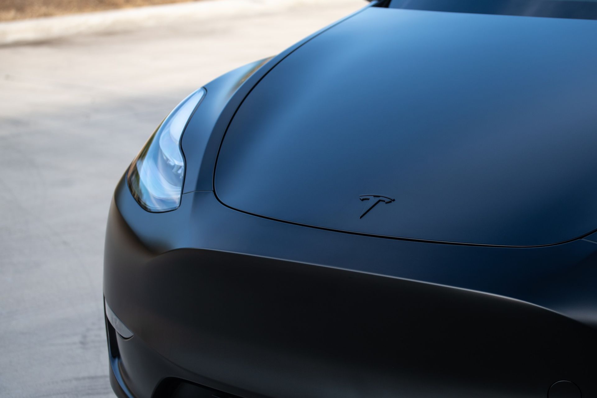 A close up of the hood of a black tesla model 3.