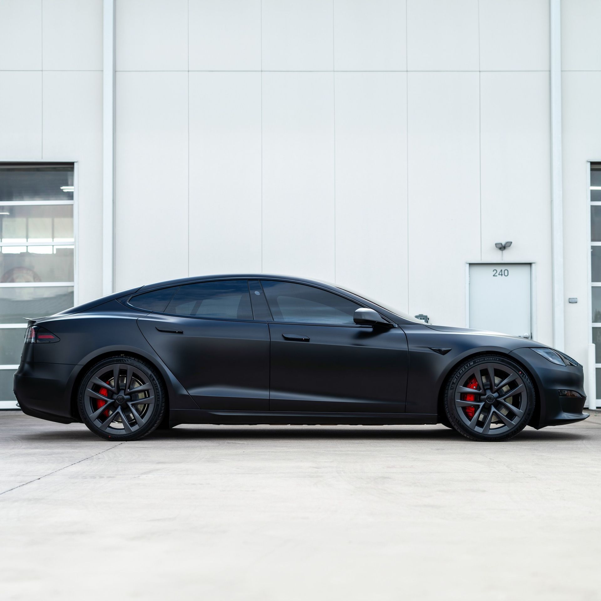 A black tesla model s is parked in front of a white building.
