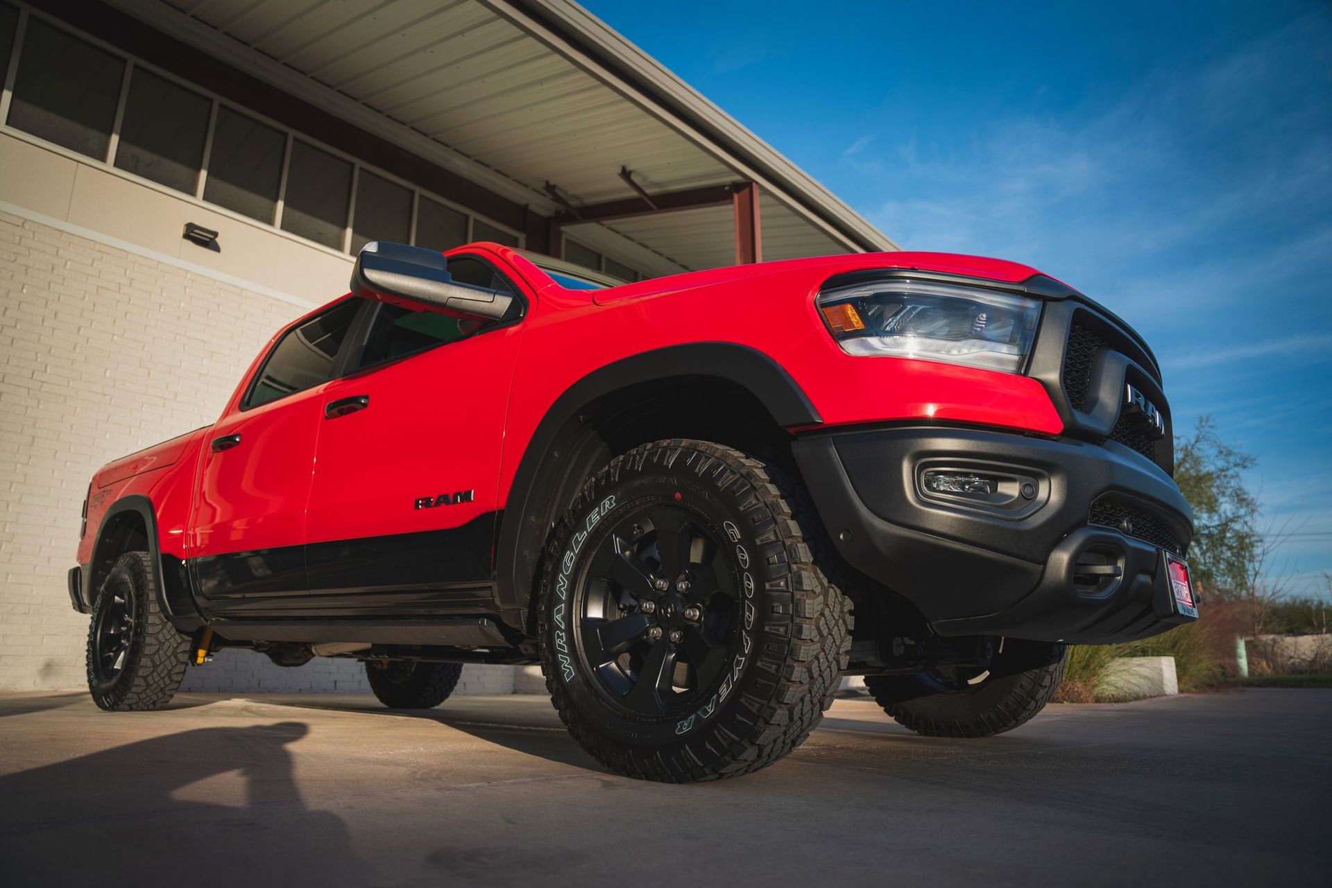 A red ram truck is parked in front of a building.