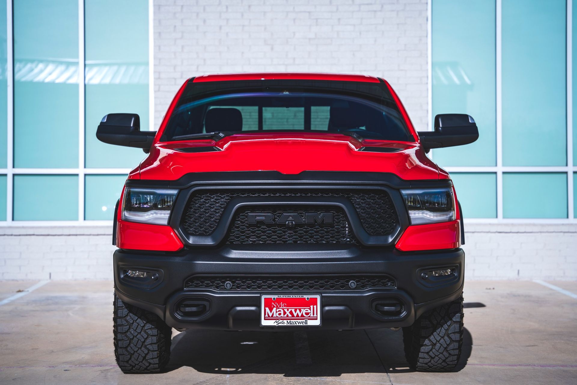 A red ram truck is parked in front of a building.