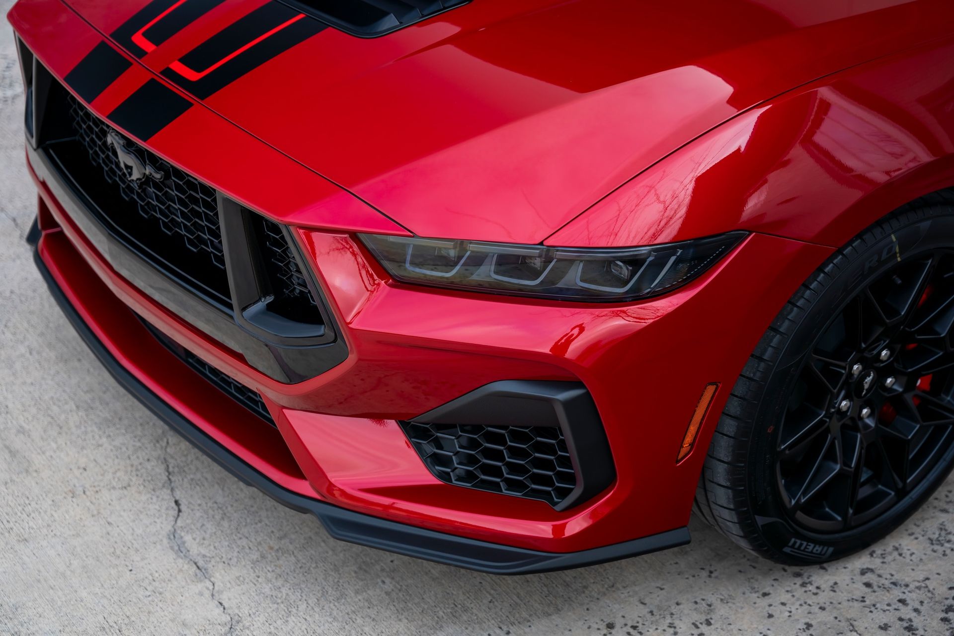 Red Ford Mustang with black stripes and wheels, close-up of the front.