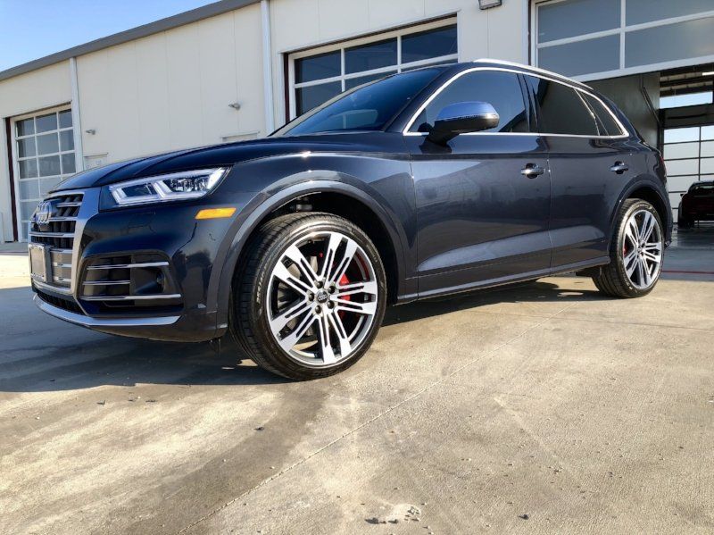 A black audi q5 is parked in front of a garage.