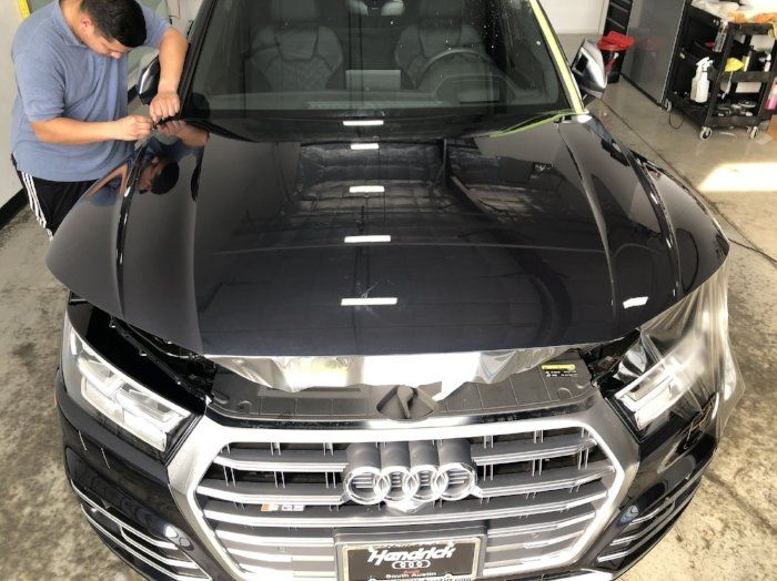 A man is working on the hood of an audi car.