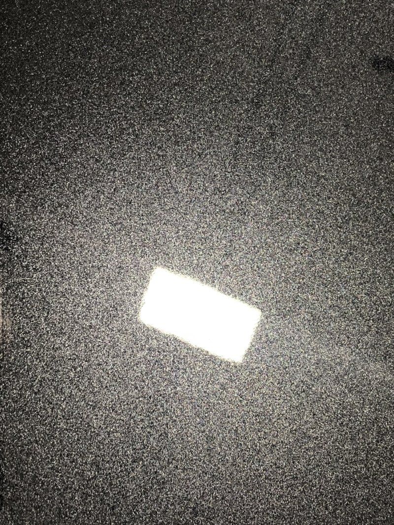 A white rectangle is sitting on top of a black carpet.