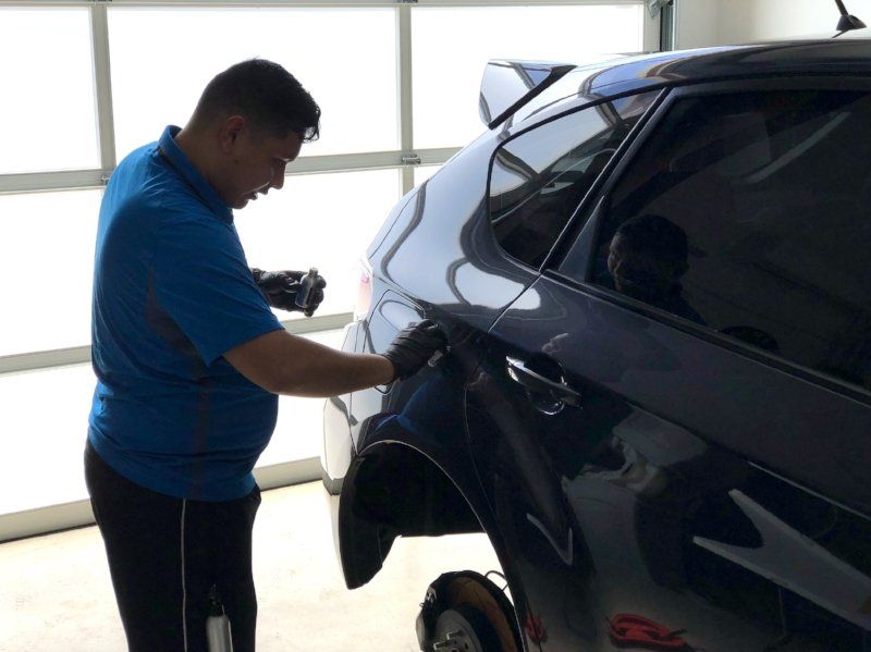 A man in a blue shirt is working on a car
