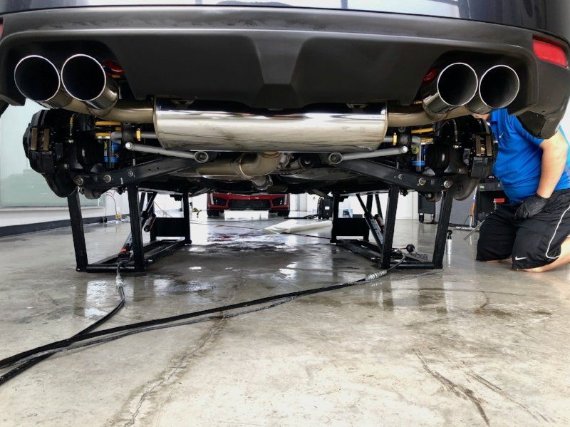 A man is working on the underside of a car on a lift.