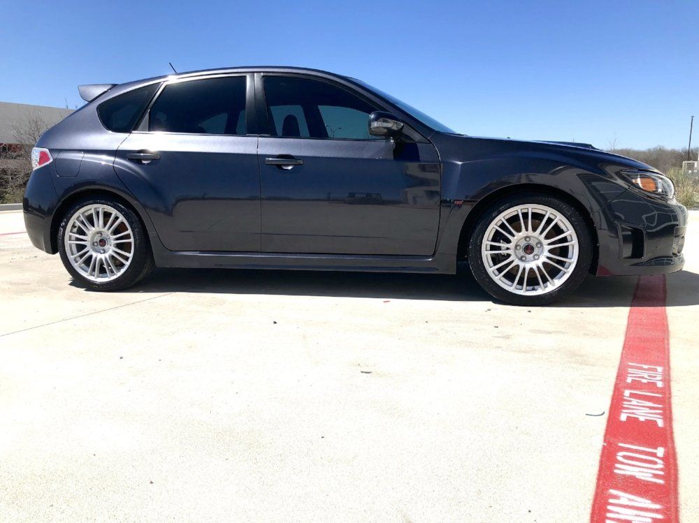 A black subaru wrx sti is parked in a parking lot.