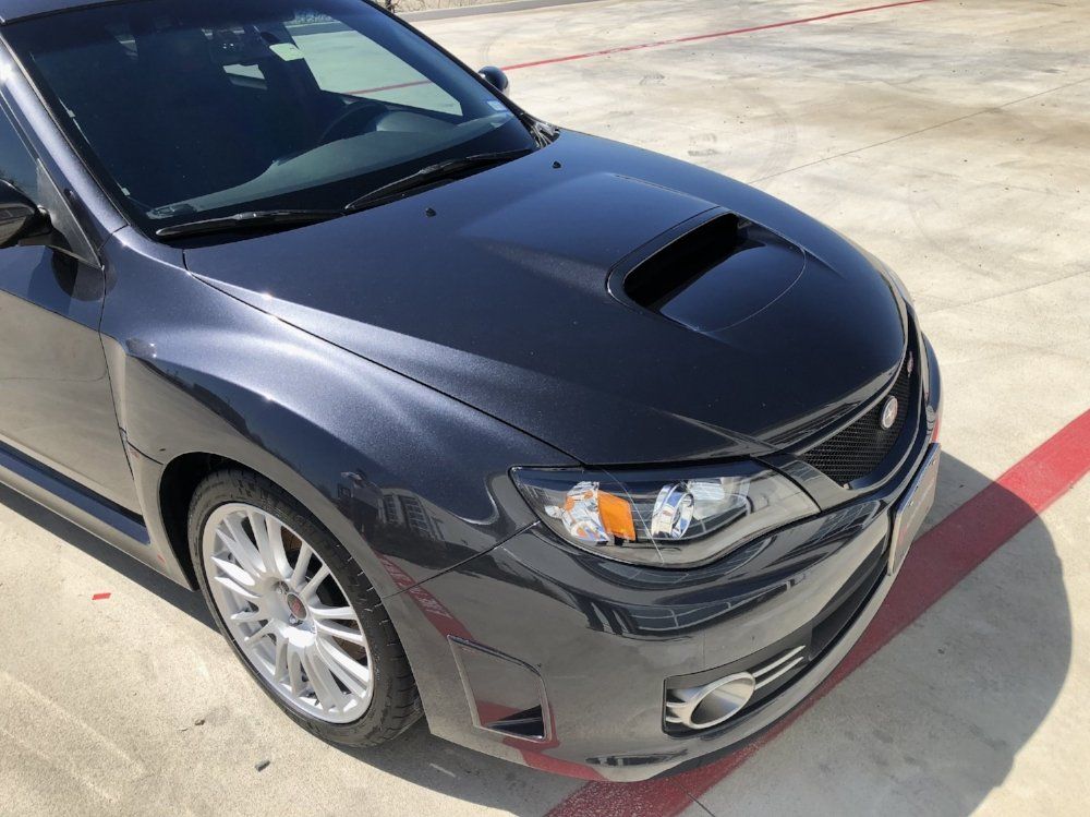 A black subaru is parked in a parking lot