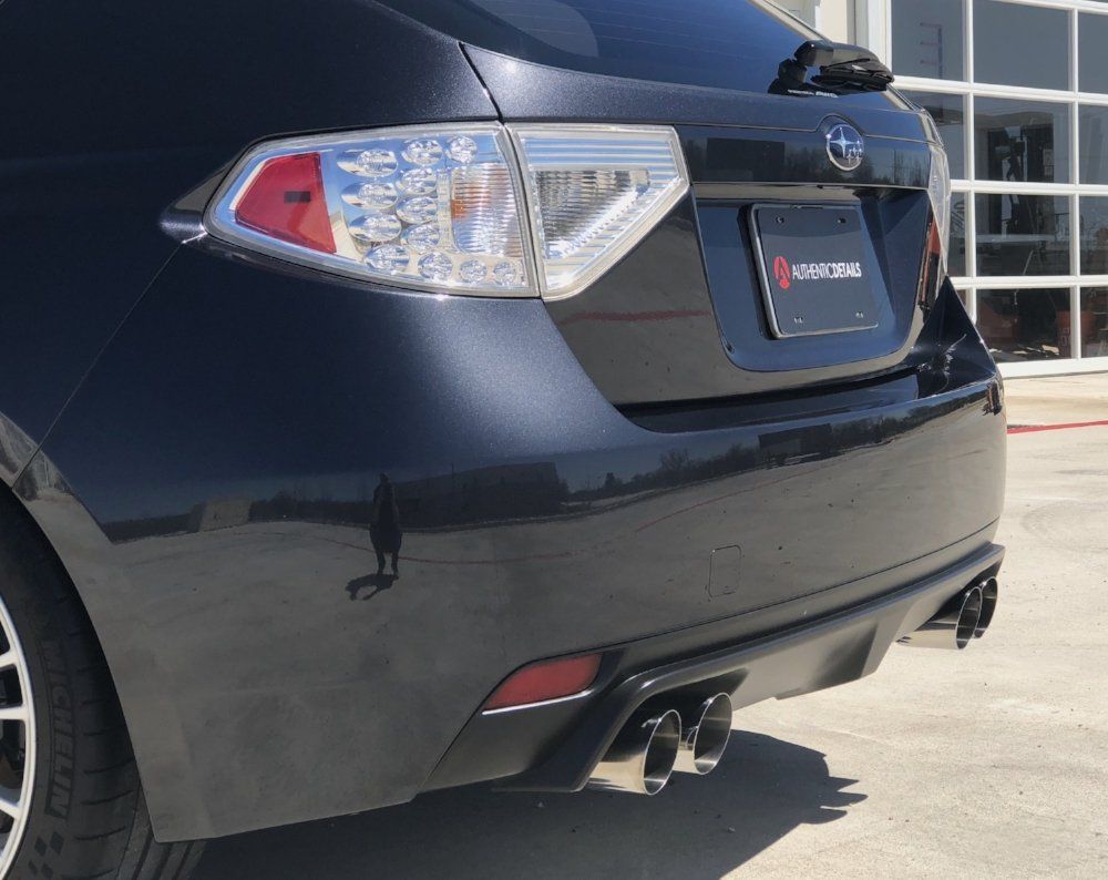 A black subaru is parked in front of a garage door