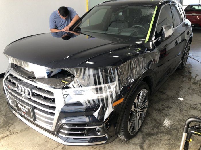 A man is working on the hood of a black audi q5.