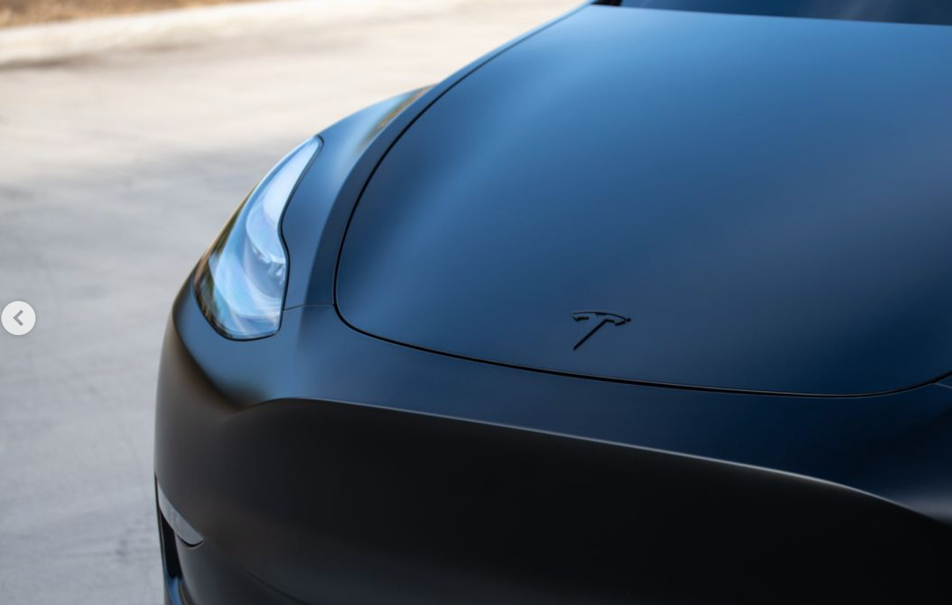A close up of the hood of a black tesla model 3.