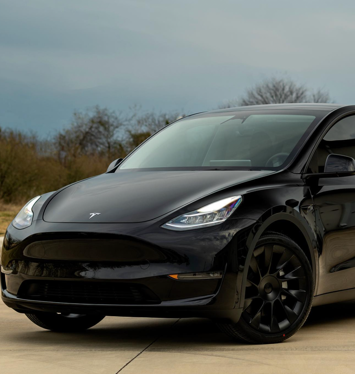 A black tesla model y is parked on the side of the road