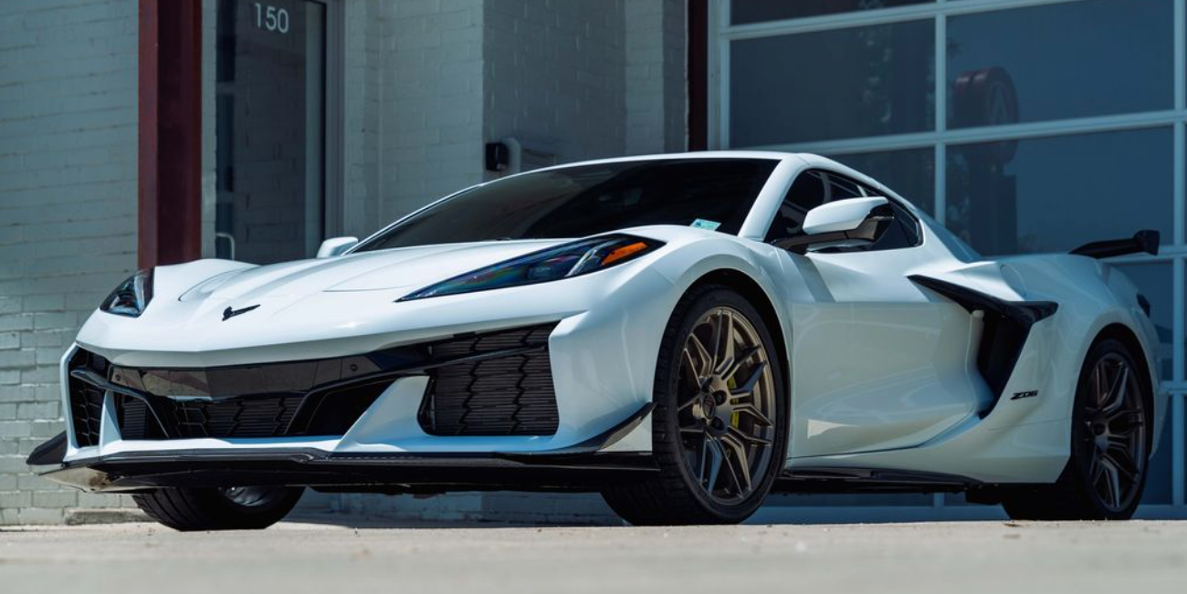 White sports car parked in front of a building with a garage door, parked outside.