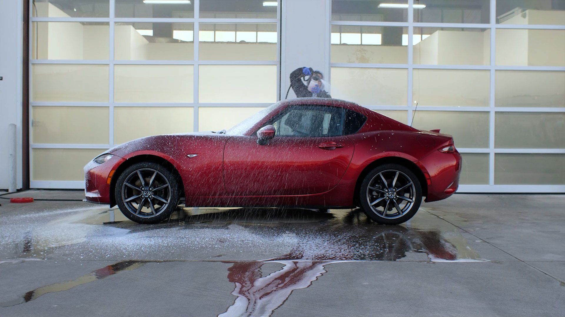 A red sports car is parked in front of a garage door.