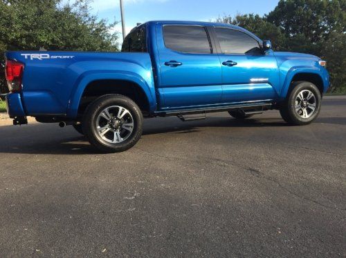 A blue toyota tacoma truck is parked on the side of the road