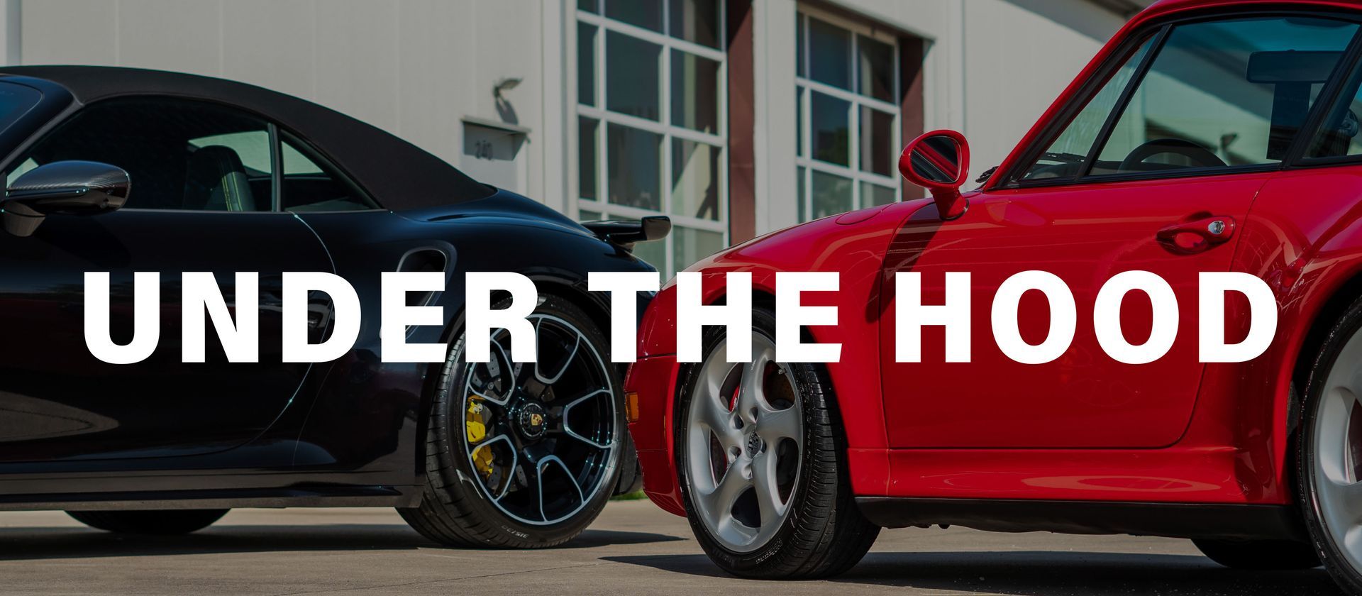 Two sports cars are parked next to each other under the hood.