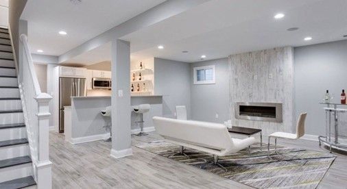 A living room in a basement with a couch , fireplace , and stairs
