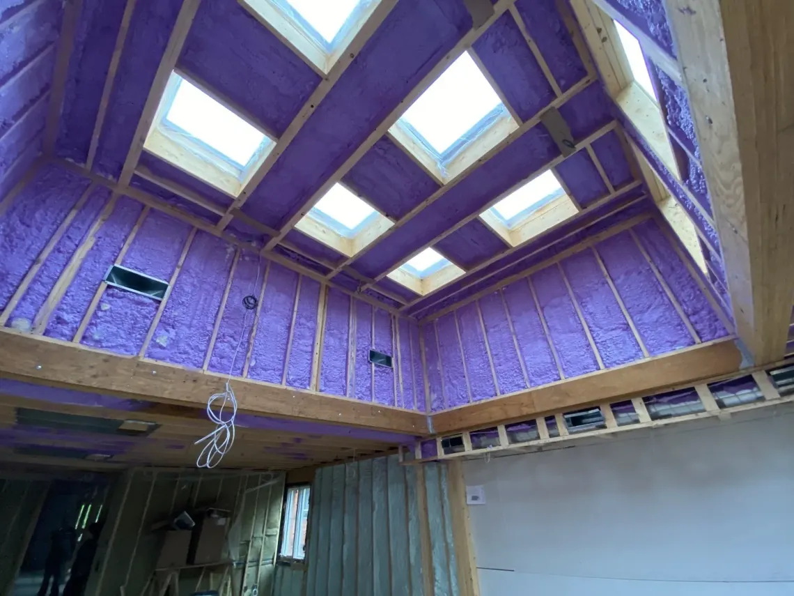 An empty attic with wooden beams and insulation.