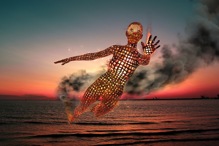 A statue of a man is floating in the ocean at sunset.
