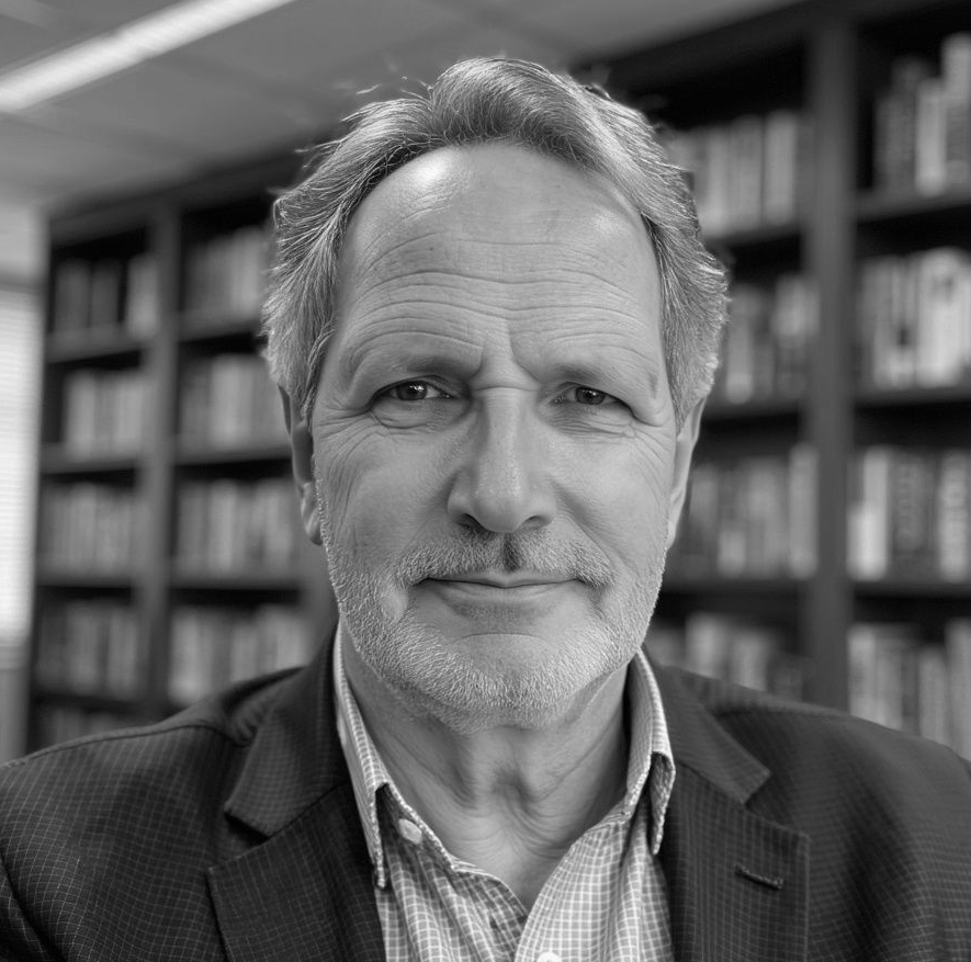 A man in a suit and tie is smiling in a black and white photo