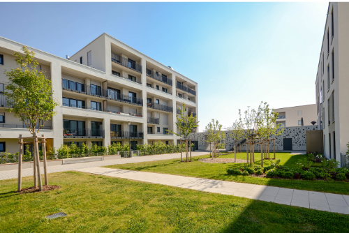 A large apartment building with a lush green lawn in front of it.