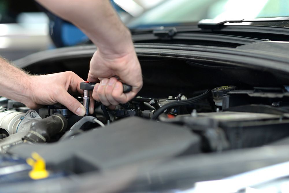 A Man Is Working On The Engine Of A Car With A Wrench — Macgregor Auto In Belconnen, ACT