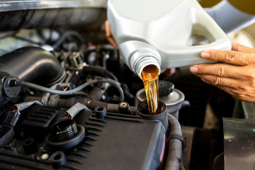 A Person Is Pouring Oil Into A Car Engine — Macgregor Auto In Belconnen, ACT