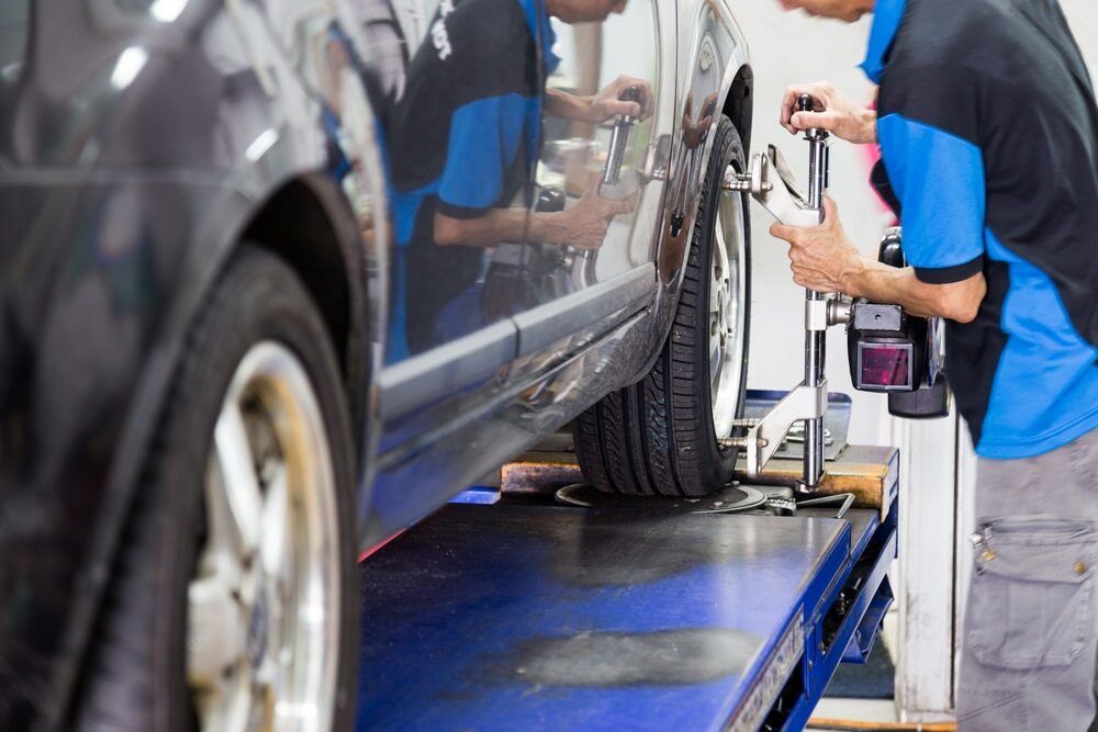 A Man Is Working On A Car On A Lift In A Garage — Macgregor Auto In Belconnen, ACT