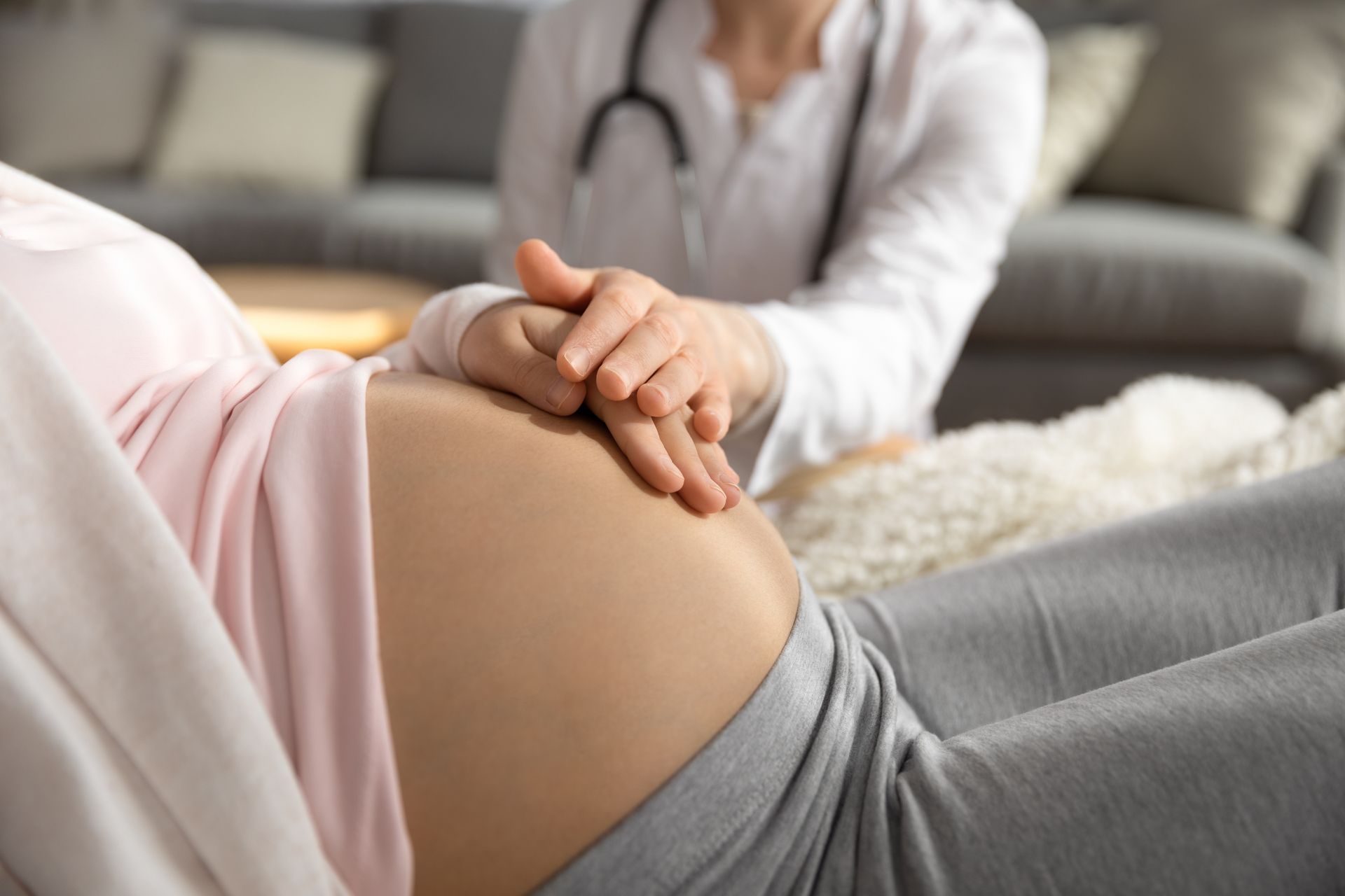 Person gently holding a pregnant belly on a sofa during a counseling session