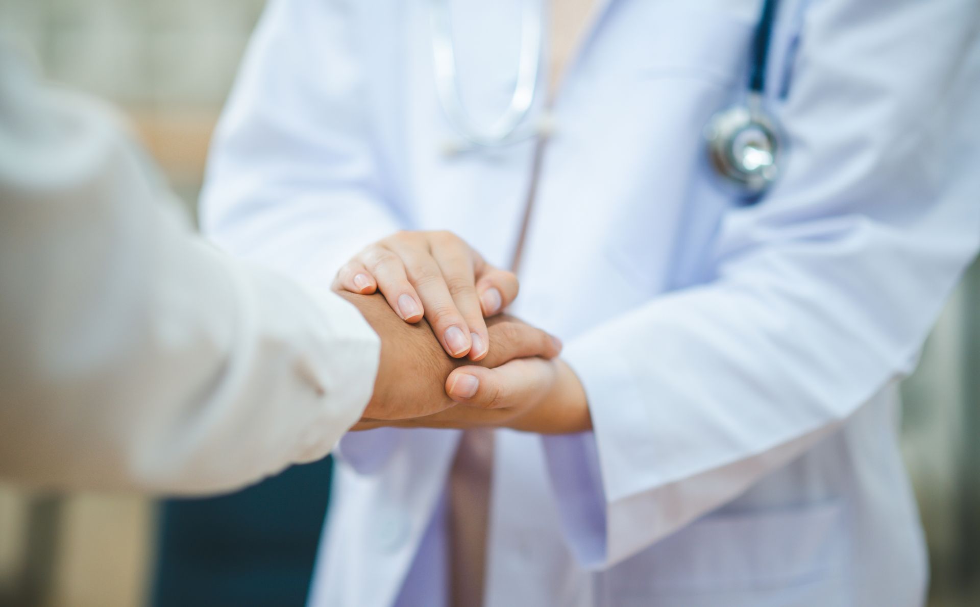 Doctor holding a patient’s hand in a caring hospital setting