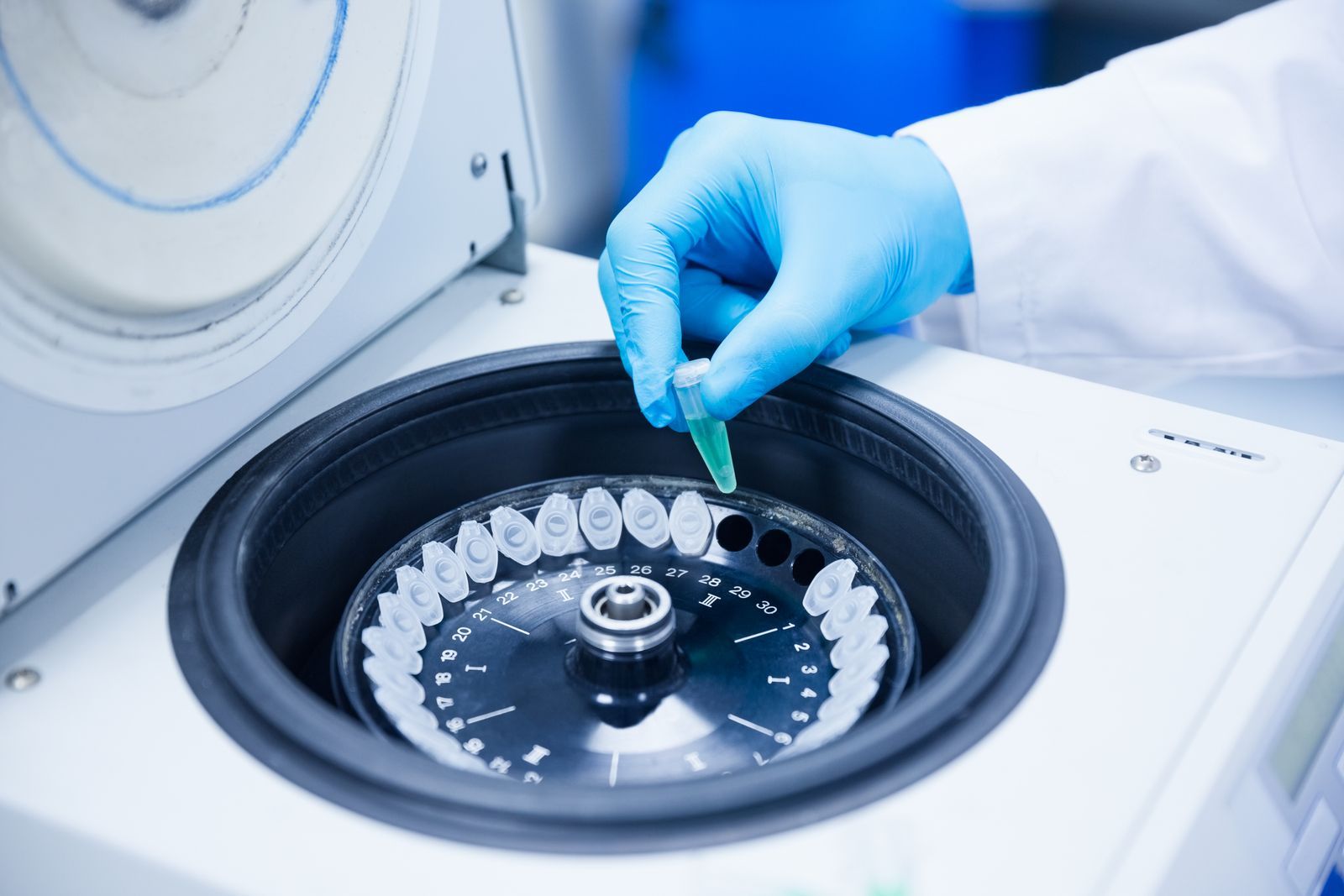 A person is putting a pipette into a centrifuge.