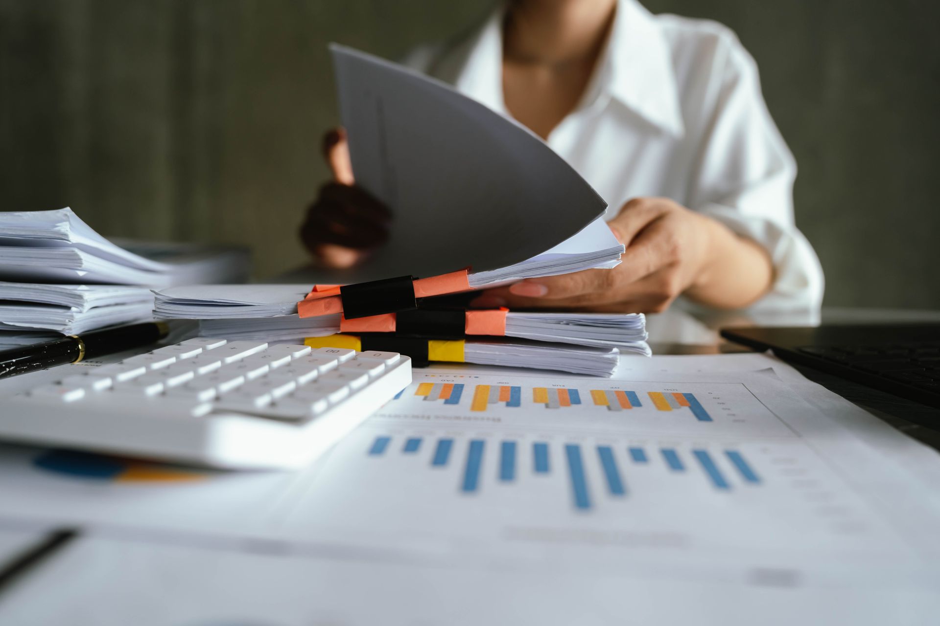 Person reviewing charts and papers at a desk with a calculator and documents