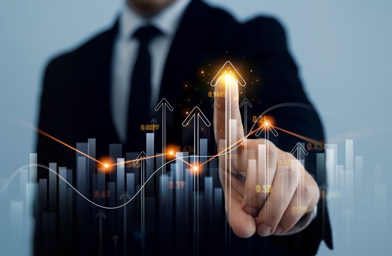 Business person pointing at glowing upward chart and bar graph on a digital interface