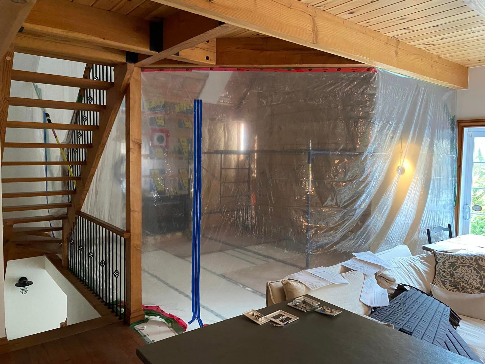 A living room with a staircase and a plastic covering on the floor.