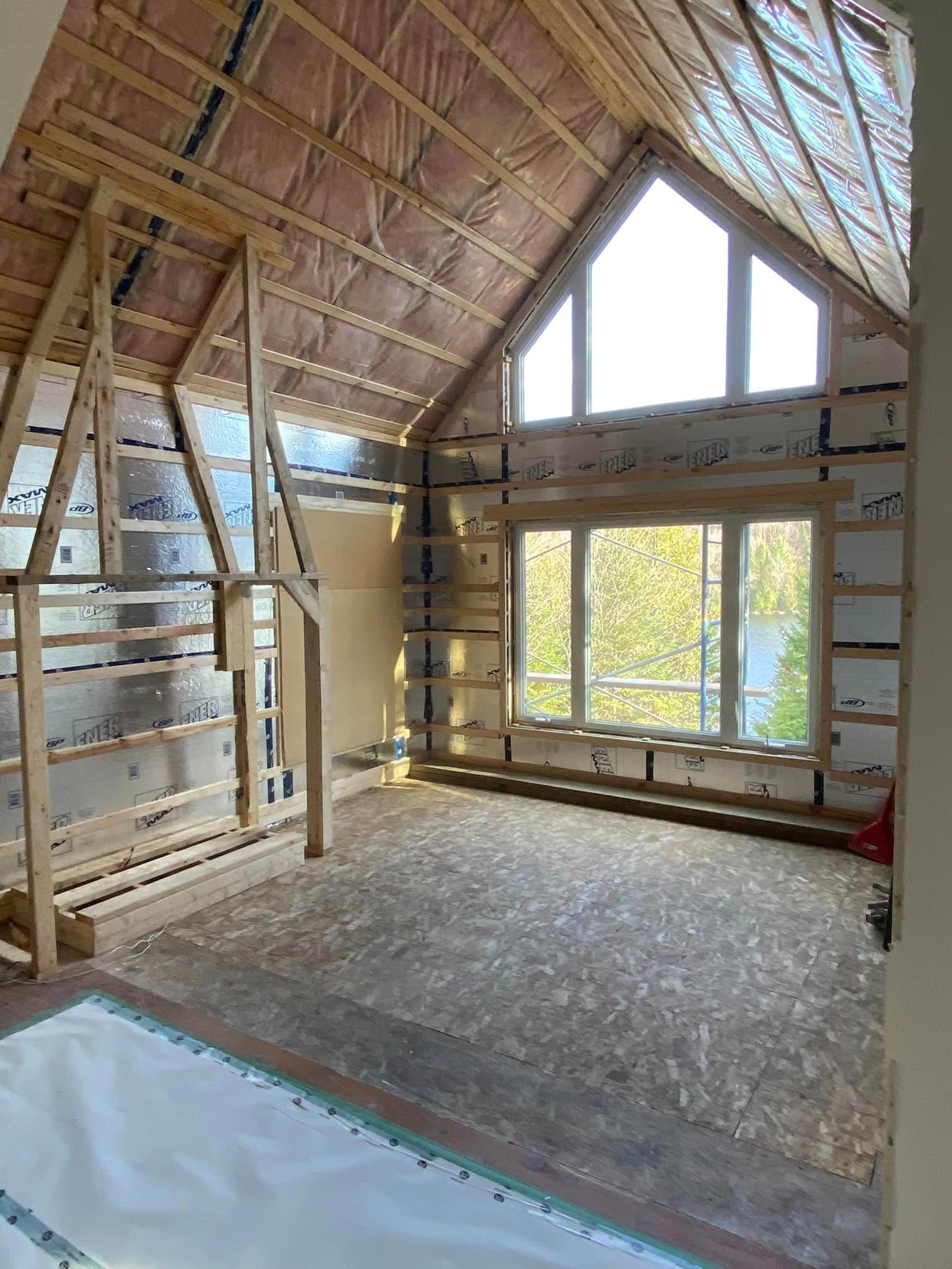 A room in a house under construction with a lot of windows.