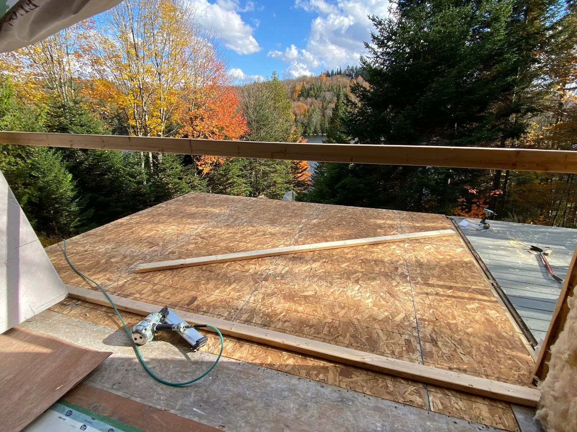 A roof is being built with a view of a lake and trees in the background.