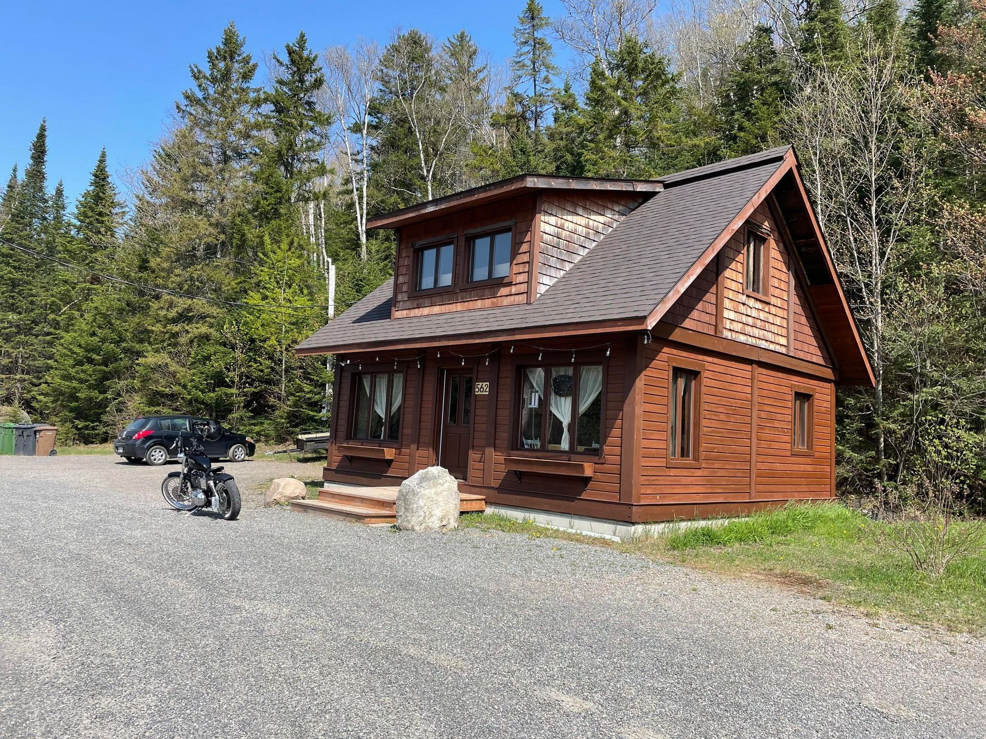 A small wooden house with a motorcycle parked in front of it.