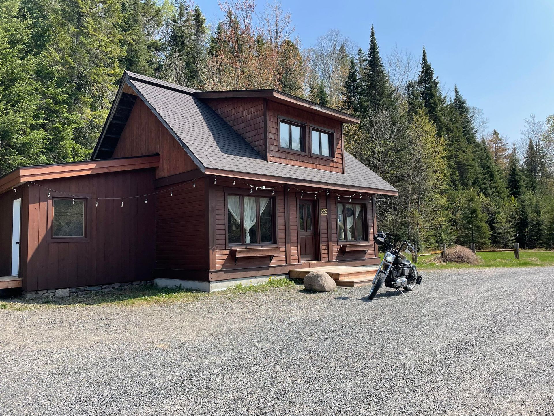 A motorcycle is parked in front of a small wooden house.