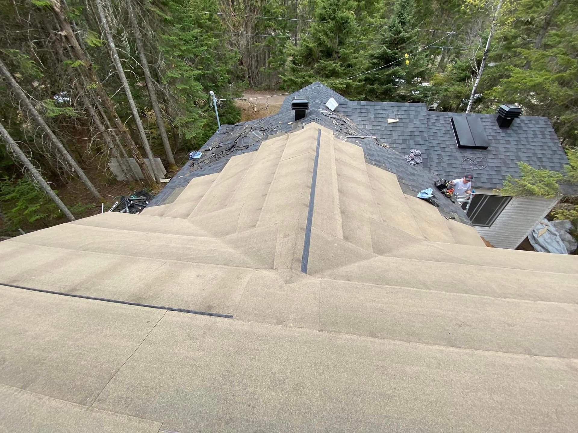 An aerial view of a roof with a pyramid shaped roof and trees in the background.