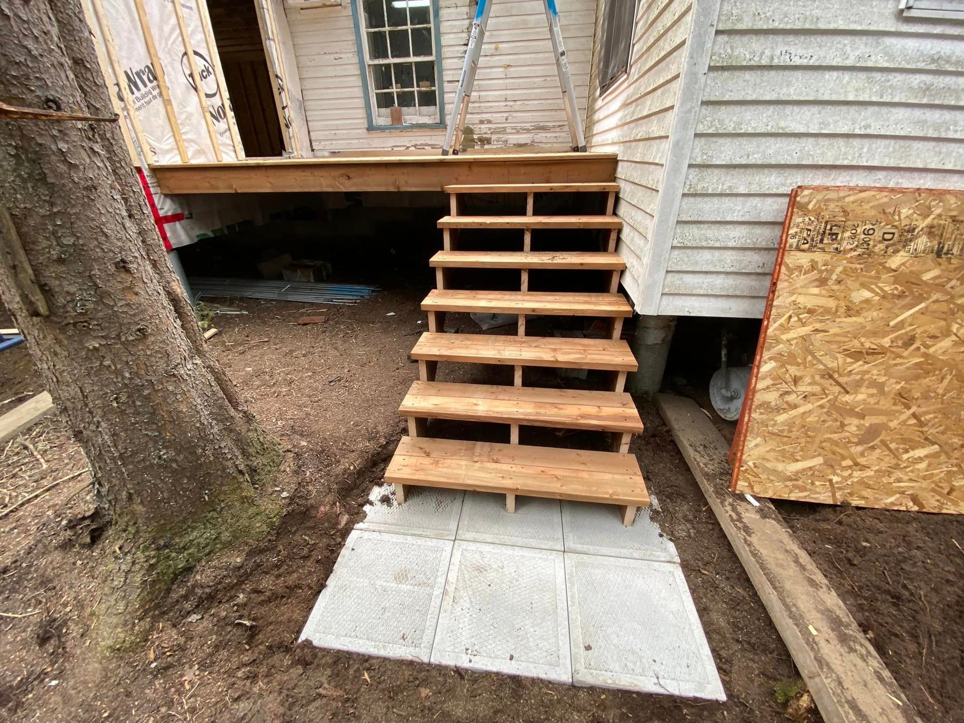A set of wooden stairs leading up to a house under construction.
