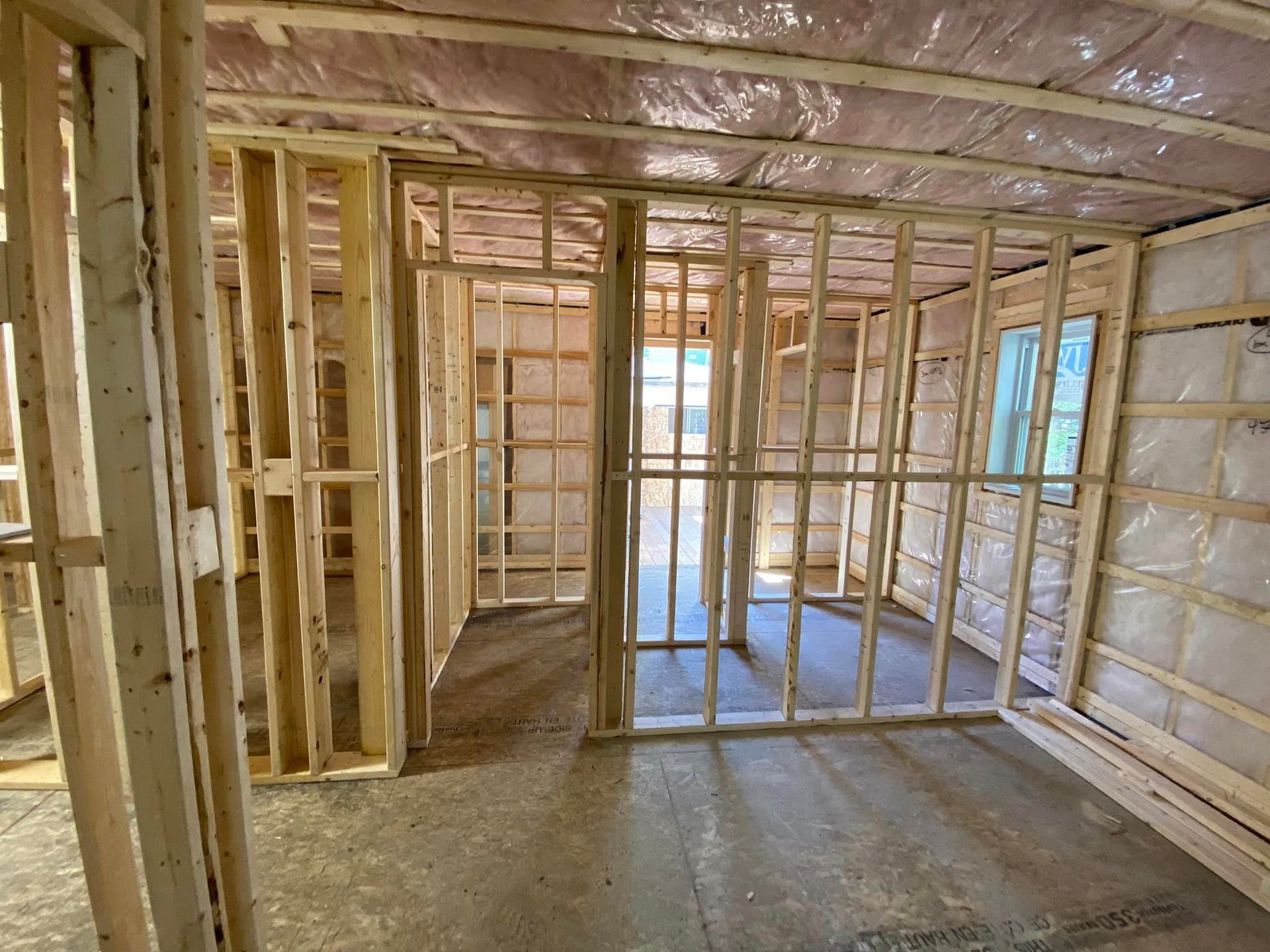 A room in a house under construction with wooden frames and insulation.