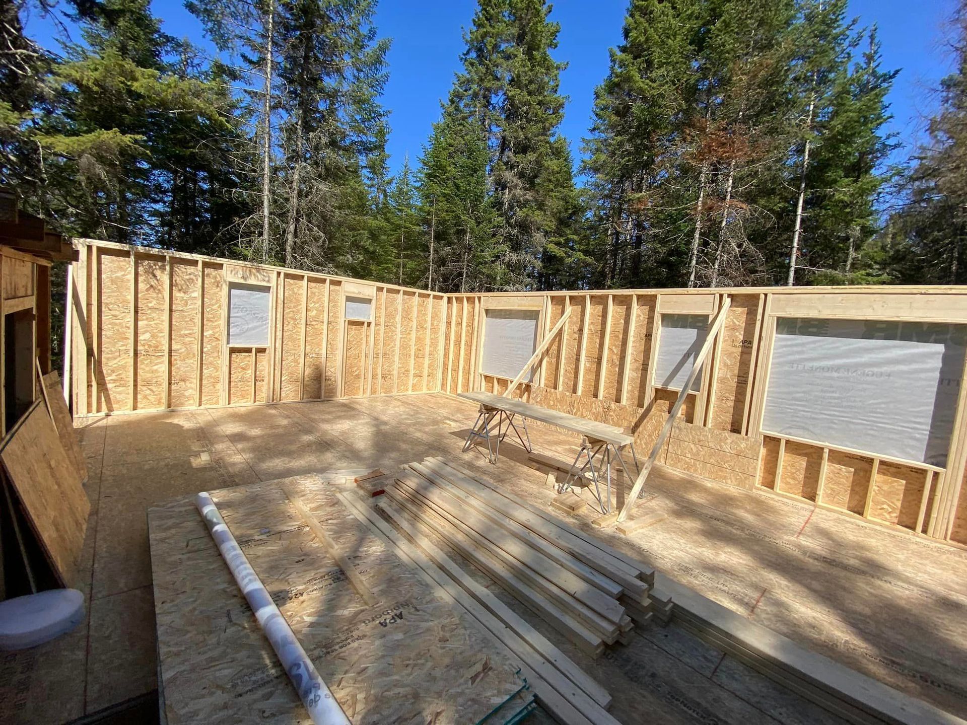A large wooden structure is being built in the middle of a forest.