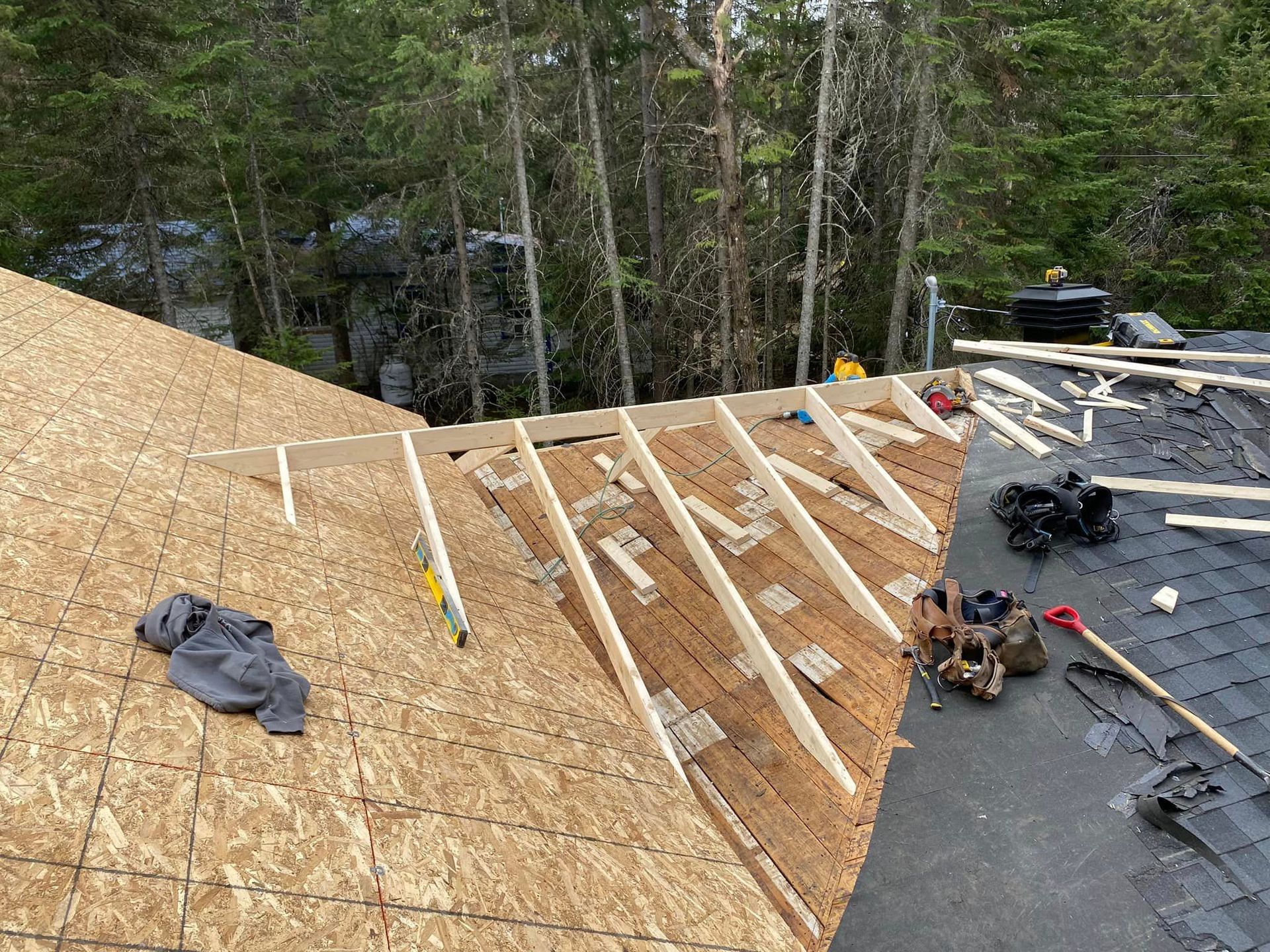 A roof is being built with wooden beams and shingles.