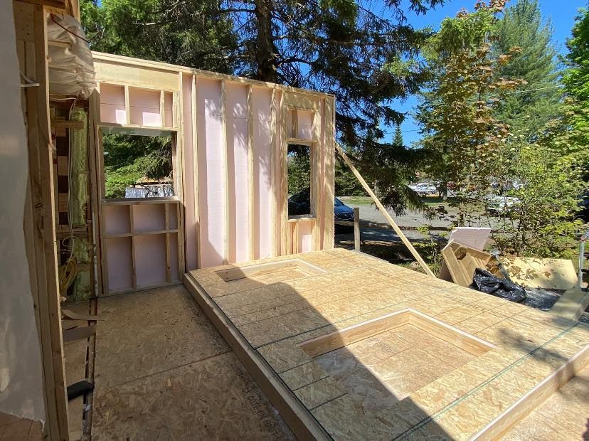 A wooden structure is being built in a backyard with trees in the background.