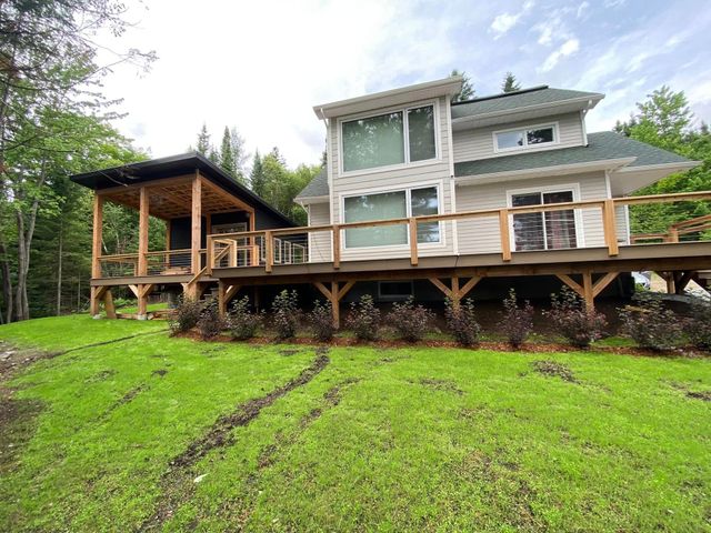Une grande maison avec une grande terrasse au milieu d'un champ verdoyant.