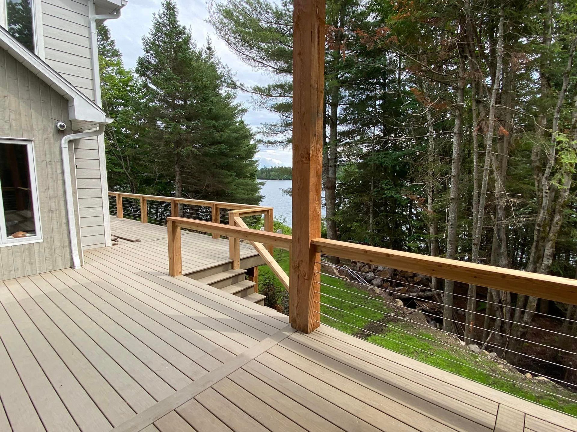 A wooden deck with a view of a lake and trees.