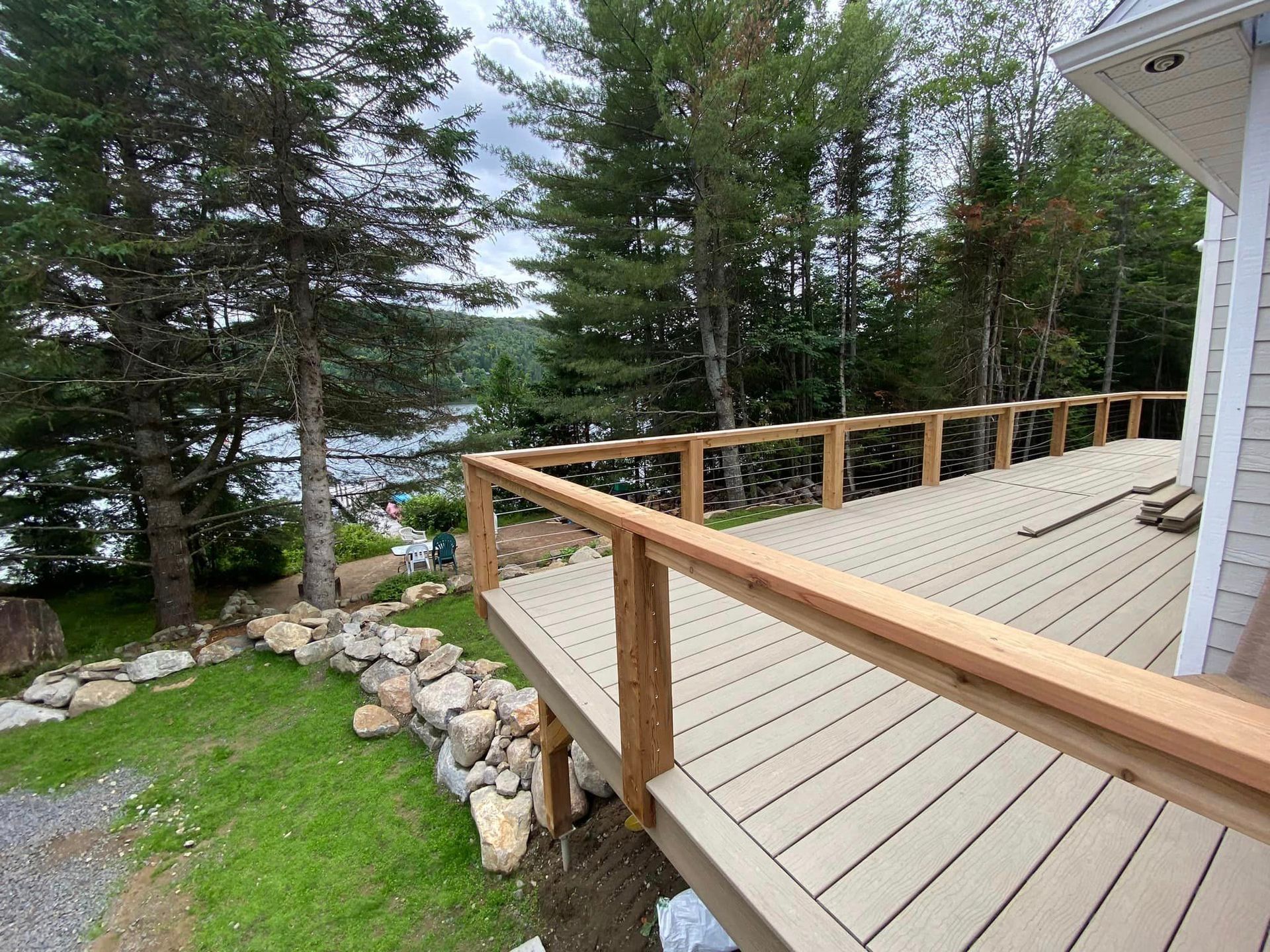 A deck with a wooden railing and a view of a lake surrounded by trees.