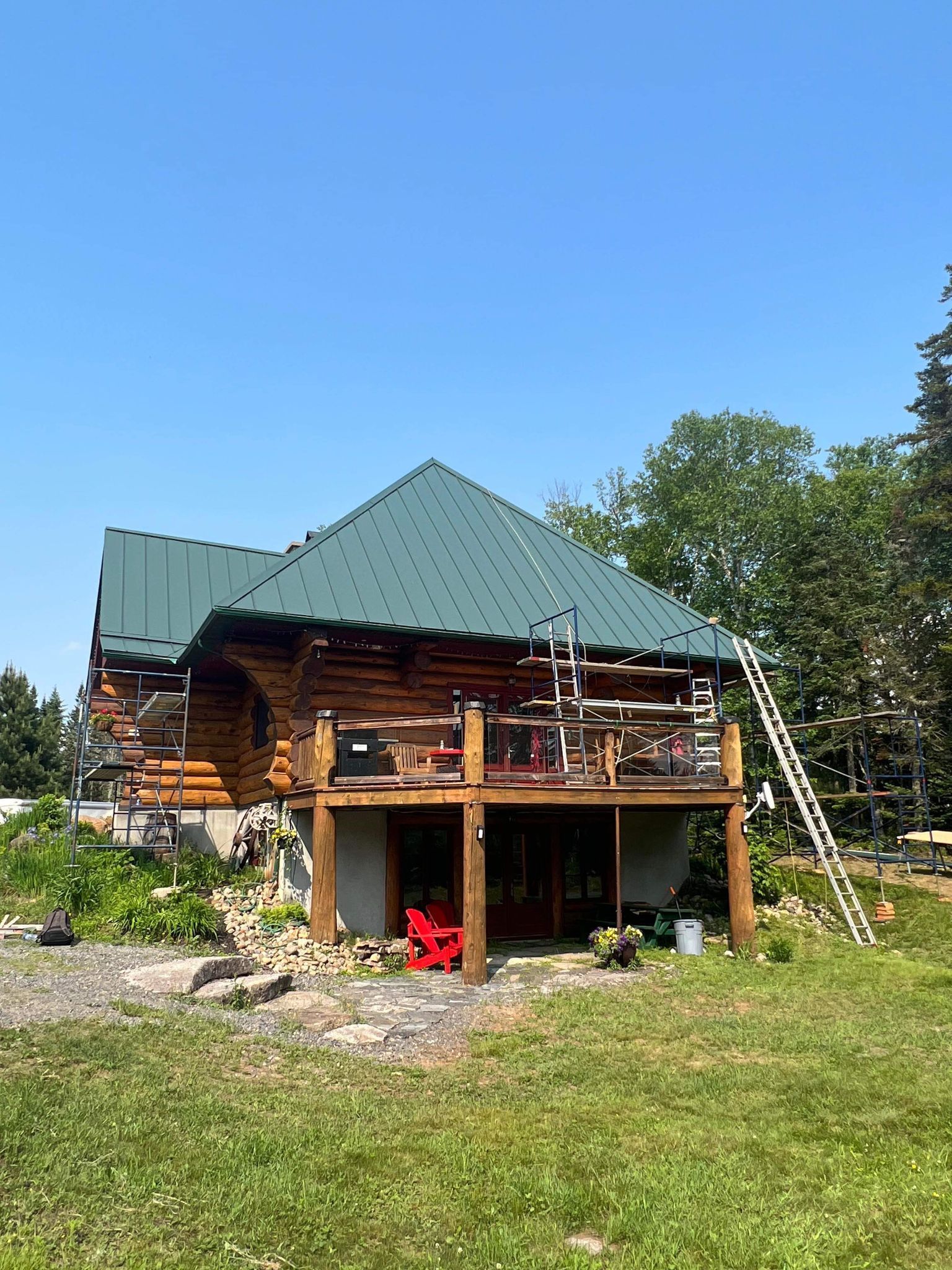 A log cabin with a green roof is sitting on top of a lush green field.