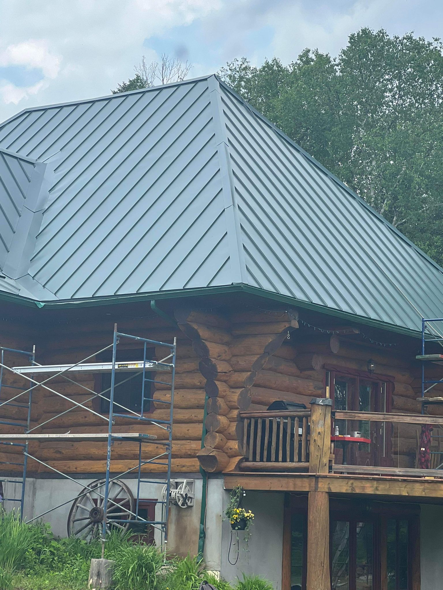 A log cabin with a metal roof and a deck.